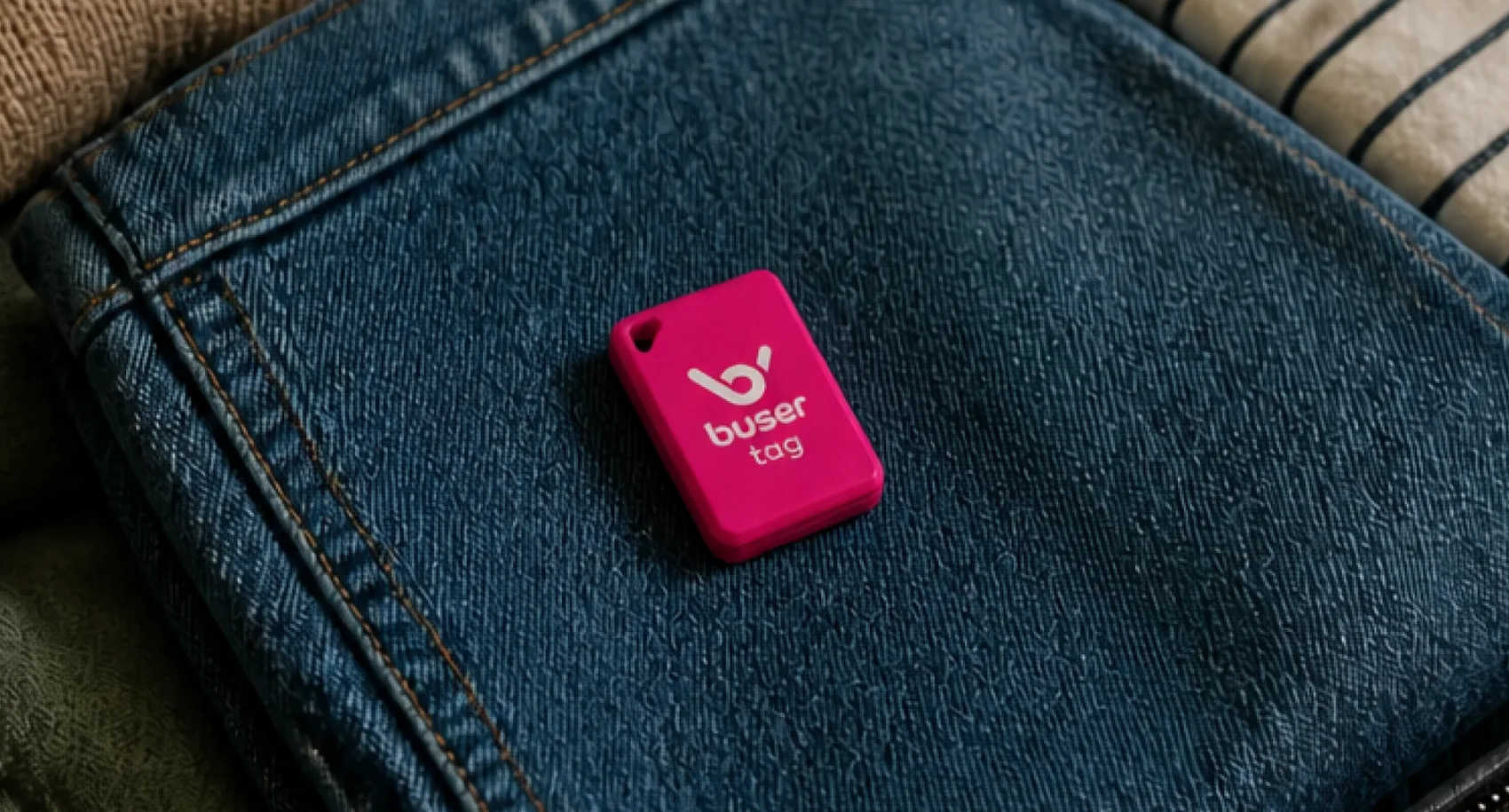 Uma buser tag rosa sobre as roupas dobradas dentro de uma mala aberta.
